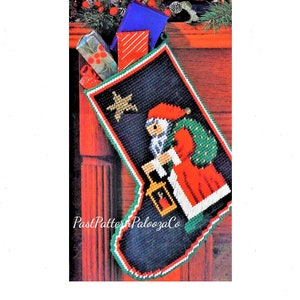 May include: A green, red, and white Christmas stocking with a Santa Claus design. Santa is holding a lantern and has a bag of gifts on his back. The stocking is filled with wrapped gifts.