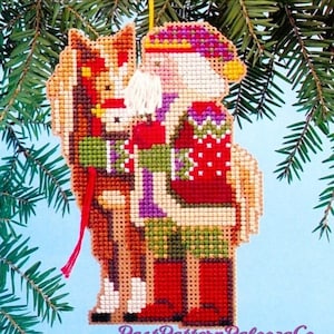 May include: A cross-stitch pattern for a Christmas ornament featuring Santa Claus riding a horse. The ornament is red, green, white, and brown. The text "EQUINE SANTA" is at the bottom of the image.