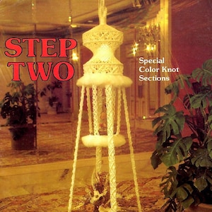 以下が含まれることがあります： 白いマクラメ製の吊り下げ式プランターホルダーで、丸いガラスの天板と白いふわふわのトリムが付いています。プランターホルダーは、模様のあるカーペットと植物のある部屋の天井から吊り下げられています。画像には「STEP TWO」と「Special Color Knot Sections」のテキストが表示されています。