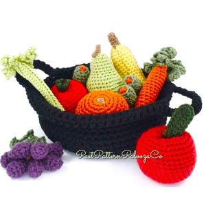 May include: A black crocheted basket overflowing with colorful crocheted fruits and vegetables. The basket contains a tomato, orange, pear, carrot, and banana. A bunch of purple grapes and a red apple are next to the basket. The text "Past Pattern Palooza Co" is on the image.