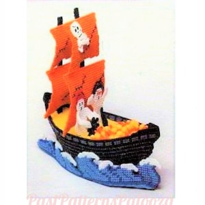 May include: A crocheted Halloween ghost ship with orange sails and a black hull. The ship is filled with orange and yellow candy corn and has three white ghosts on board.