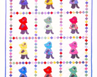 Puede incluir: Un edredón hecho a mano con un patrón repetido de figuras que llevan sombreros y vestidos de varios colores. El edredón está bordeado con un borde azul y un patrón de diamantes multicolores. El texto "PastPatternPalooza Co" es visible en la esquina inferior derecha.