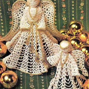May include: Two crocheted angel ornaments with gold trim. The angels are white and have a delicate lace design. They are sitting on a green background with gold ornaments.