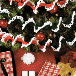 May include: A Christmas tree decorated with a white and red crocheted garland. The garland is made of a series of loops and is draped around the tree. The tree is also decorated with red baubles.