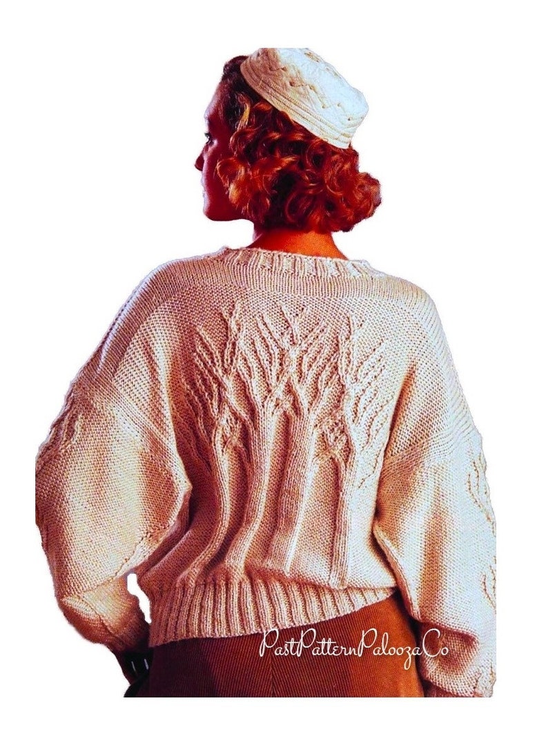May include: Cream-colored, oversized knit sweater with a textured leaf design on the back. The sweater has long sleeves and a ribbed hem. A matching knit hat is also visible. The image is from PastPatternPaloozaCo.