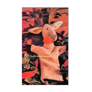 May include: A brown and white reindeer puppet with a red collar and silver jingle bells. The puppet is sitting in a wooden sled with the word "FLYER" printed on it.