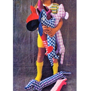 May include: A young girl holds four colorful dachshund-shaped stuffed toys. The toys are made of fabric with a checkered pattern and have embroidered eyes and noses. The girl is wearing a striped shirt and yellow socks.