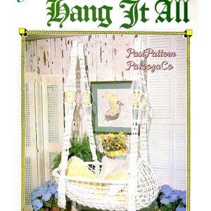 May include: A white macrame hanging cradle with yellow checkered cushions, featuring the text Juliano's Hang It All Book 3 and Snow Flake Cradle. The cradle is suspended by intricate knotted cords with circular accents and decorative fringe details.