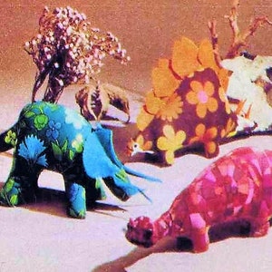 Op de afbeelding: Vier pluche dinosaurus speelgoed met bloemenpatronen. De dinosaurussen zijn een blauwe triceratops, een bruine stegosaurus, een roze ankylosaurus en een witte brachiosaurus.