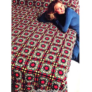 May include: A red, green, yellow, and black crochet blanket with a geometric pattern. A woman is lying on the blanket.