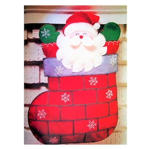 May include: A red felt stocking with a brick pattern and white snowflakes. A Santa Claus face is peeking out of the top of the stocking.