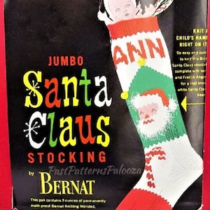 May include: A vintage knitting pattern for a Jumbo Santa Claus stocking by Bernat. The pattern features a colorful design with a Santa Claus face, the name "ANN", and a baby peeking out of the stocking. The package contains 3 ounces of yarn.