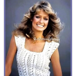 Puede incluir: Una mujer con un top blanco de ganchillo sin mangas con cuello cuadrado. El top presenta un patrón calado. La mujer tiene el pelo largo y rubio ondulado y está sonriendo. La imagen tiene una estética vintage.