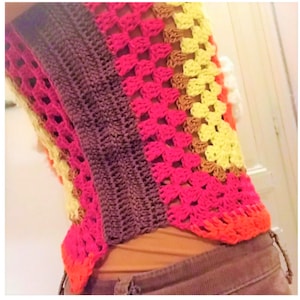 Op de afbeelding: Een veelkleurig gehaakt topje met een kleurenschema van bruin, roze, oranje, geel en wit. Het topje is gemaakt met een granny square steekpatroon.
