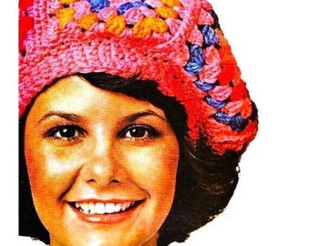 May include: A colorful, crocheted hat in shades of pink, orange, yellow, and blue. The hat is a granny square design, with a rounded crown and a brim. The text "PastPatternPaloozaCo" is visible in the image.