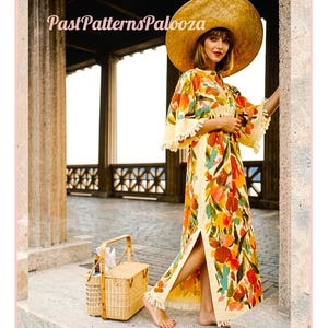May include: A floor-length cream-colored dress featuring a vibrant floral print in shades of orange, yellow, and green, with wide sleeves and a fringed hem. The dress includes the text PastPatternsPalooza and is paired with a large straw hat.