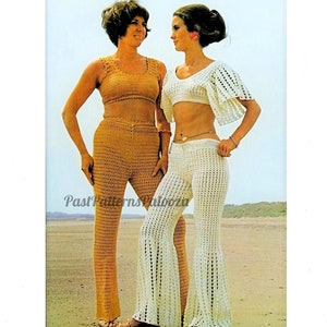 May include: Two women wearing crocheted pants and tops. The woman on the left is wearing a brown crocheted outfit, and the woman on the right is wearing a white crocheted outfit. Both women are standing on a sandy beach.