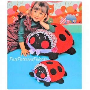 May include: Two plush ladybug toys in red and black with black spots. Each ladybug features a white lace bonnet, a lavender ribbon bow, and red circular cheeks. The text PastPatternsPalooza is printed in white script across the center area.
