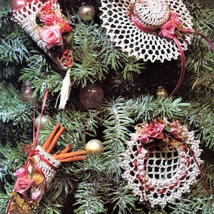 May include: Four crocheted Christmas ornaments in white with pink accents. The ornaments are a cone with red berries, a hat, a small bag, and a doily. The ornaments are hanging on a green Christmas tree. The text "Precious Reminiscence Lace Coquetry" is at the bottom of the image.