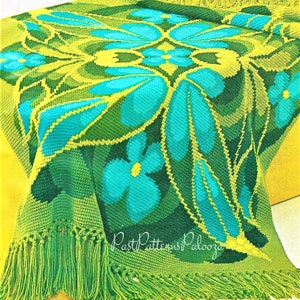 Peut inclure: Une couverture en crochet avec un motif floral dans les tons de vert, bleu et jaune. La couverture a une bordure en franges.