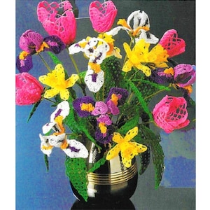 May include: A crocheted bouquet of flowers in a gold vase. The bouquet includes pink tulips, yellow daffodils, and purple and white irises.