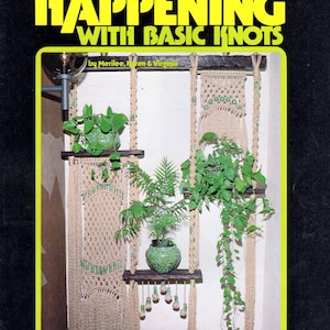 May include: A book cover with the title "Create a Happening with Basic Knots" by Merilee, Iren & Virginia. The cover features a photo of a wall hanging made with macrame and plants.