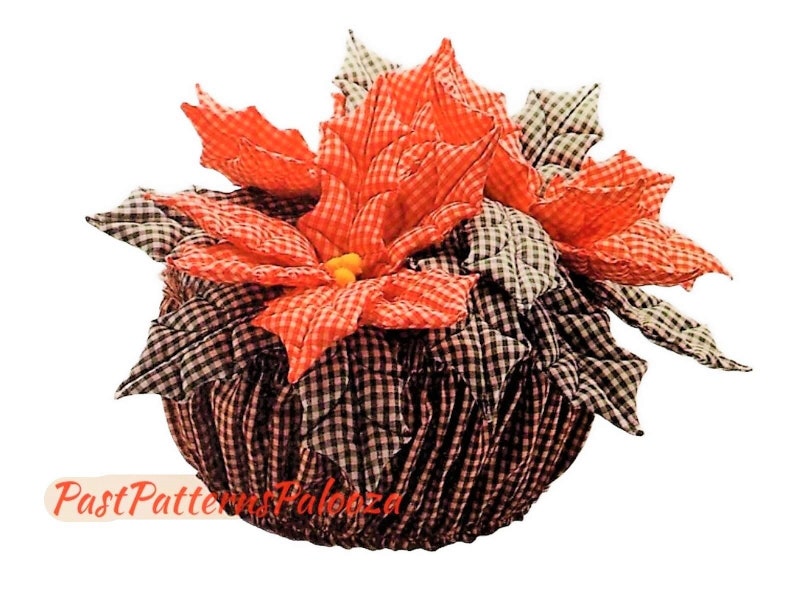 Peut inclure: Une composition florale de poinsettia en tissu vichy rouge et blanc dans un pot en tissu vichy noir et blanc. L'arrangement est un article artisanal.