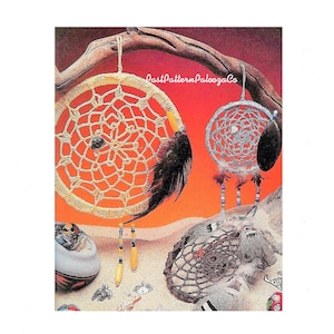 May include: Two crocheted dreamcatchers with feathers and beads hanging from them. The dreamcatchers are on a sandy background with a branch behind them. The larger dreamcatcher is beige and the smaller one is silver.
