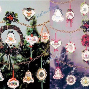 Puede incluir: Se muestra una colección de adornos navideños, incluyendo campanas, corazones y coronas. Los adornos están adornados con diseños festivos y texto, suspendidos de una cadena contra un fondo borroso de árboles de hoja perenne.