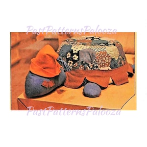 May include: A handmade turtle-shaped pincushion with a patchwork shell, orange felt trim, and a blue body. The turtle has an orange felt hat and a small blue stone. The text "Past Patterns Palooza" is visible.