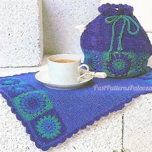 May include: A crocheted teapot cozy in blue and green with a matching crocheted coaster. The cozy has a drawstring closure and a tassel. The coaster has a scalloped edge.