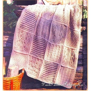 May include: A crocheted blanket with a beige color and a variety of patterns. The blanket is draped over a wooden fence and a wicker basket is in the foreground. The text "Past Patterns Palazzo Co." is visible in the bottom right corner of the image.