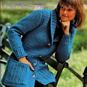 May include: A blue crocheted cardigan with a shawl collar, button front, and two patch pockets. The cardigan is shown on a model wearing black pants.