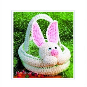 May include: A white crocheted Easter basket shaped like a bunny with pink inner ears, a pink nose, and blue eyes. The basket has a handle and is set against a green background. The text "Past Patterns Palooza" is visible.