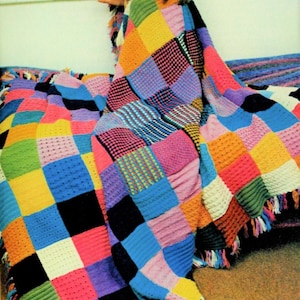 May include: A colorful crocheted blanket with a patchwork design. The blanket is made up of squares in various colors, including pink, blue, yellow, green, and purple. The blanket has fringe on the edges.