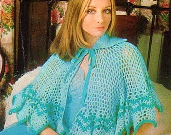 May include: A crocheted cape with a collar and tie closure. The cape is a light blue color with a darker blue trim. The cape is shown being worn by a woman with long blonde hair.