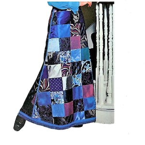 Op de afbeelding: Een lange blauwe rok gemaakt van patchwork stof in verschillende tinten blauw, paars en roze. De rok heeft een franje rand aan de onderkant.