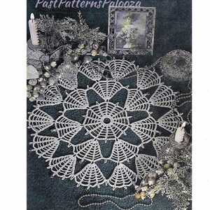 May include: A white, crocheted doily with a spiderweb design, displayed on a dark green surface. The doily is surrounded by decorative elements, including candles, a framed photograph, and beaded garlands. The text "PastPatternsPalooza" is visible.