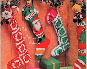 Op de afbeelding: Vier gehaakte kerstsokken hangen aan een houten paneelwand. De sokken zijn versierd met verschillende ontwerpen, waaronder een kerstman, een kerstboom en een sneeuwpop. De sokken zijn allemaal rood en groen met witte accenten. De sokken zijn allemaal ongeveer 45 cm lang.