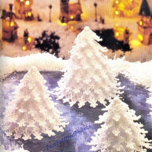 Może przedstawiać: Trzy białe, szydełkowe choinki na fioletowym tle. Choinki są różnych rozmiarów i wykonane są z koronkowego wzoru.