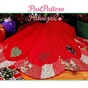 Puede incluir: Una falda de árbol de Navidad de tela roja con un borde festoneado con un patrón de patchwork de estampados florales y geométricos en rojo, blanco y verde. El centro es rojo sólido con corazones aplicados y cascabeles. Texto PastPattern PaloozaCo.