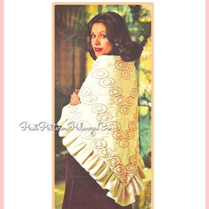 May include: A white crocheted shawl with a ruffled edge and a pattern of red embroidered circles. The shawl is draped over a person's shoulders.