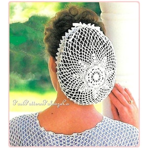 May include: A white crocheted hairnet with a circular design in the center. The hairnet is worn by a person with brown hair.