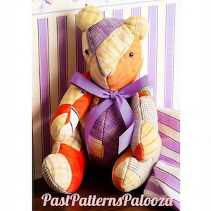 May include: A stuffed teddy bear constructed from various fabric patches in shades of orange, yellow, and purple plaid and solid colours. The bear features a purple ribbon tied around its neck and has dark eyes. The text PastPatternsPalooza is visible.