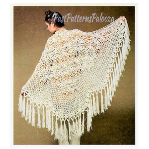 May include: A white crocheted shawl with a delicate floral pattern and fringe trim. The shawl is draped over a person's shoulders.