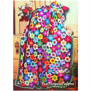 May include: A colorful crochet blanket with a black background and a green border. The blanket is made up of many small flowers in various colors, including pink, purple, blue, yellow, and green. The blanket is folded and draped over a wooden chest.