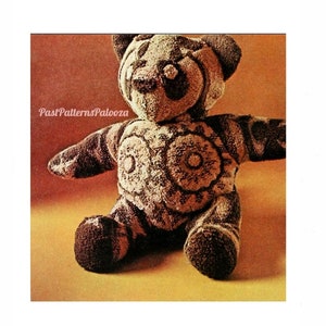 May include: A brown and white panda bear plush toy with a geometric pattern. The bear is sitting on a yellow surface.