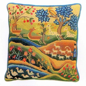 May include: A colorful needlepoint pillow featuring a pastoral scene with a blue tree, birds, and animals. The pillow has a yellow, green, and blue background with a variety of colors in the design.