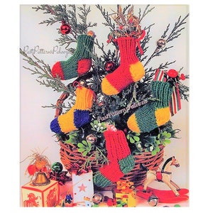 May include: Five knitted Christmas stockings in a basket. The stockings are red, green, yellow, and blue. The stockings are decorated with a white pom-pom at the top.