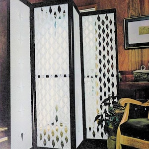 以下が含まれることがあります： ダイヤモンド模様の白い織り素材で作られた3枚のパネルの部屋仕切り。仕切りは黒い枠で、木製の壁パネルのある部屋に立っています。